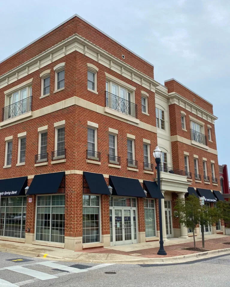 Corner view of a red brick commercial building with black awnings and large windows
