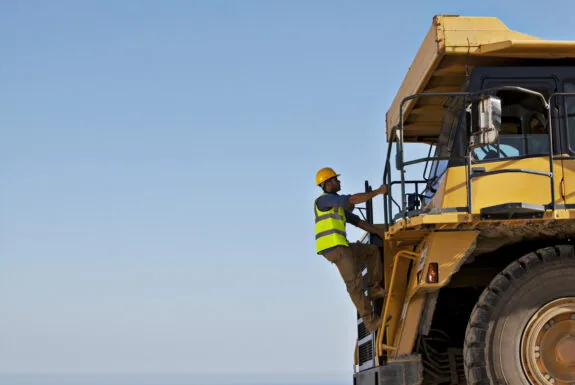 Worker climbing machinery on site