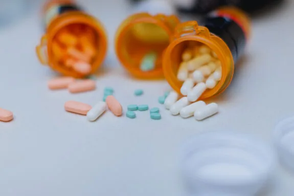 Part of daily life routine for an adult with ADHD, taking the right medication that helps them focus on daily life and achieve their goals throughout the day. These ADHD pills and other medicines are displayed with open pill bottles on top of a white counter top in the kitchen.